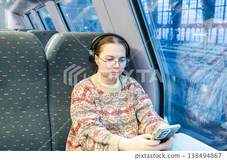 Smiling teenager girl with gallses and headphones in train Smiling teenager girl with gallses and headphones in train 138494867