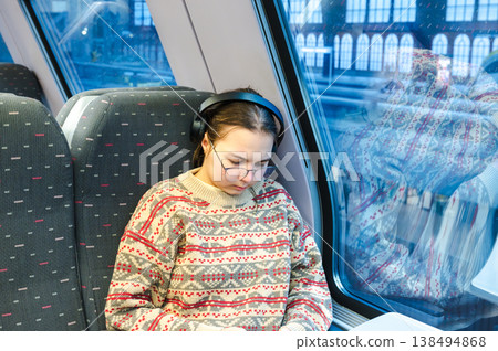 Smiling teenager girl with gallses and headphones in train 138494868