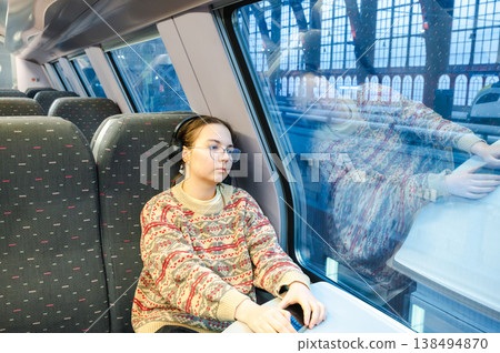 Smiling teenager girl with gallses and headphones in train Smiling teenager girl with gallses and headphones in train 138494870