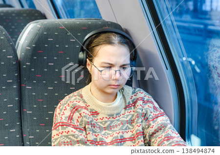 Smiling teenager girl with gallses and headphones in train 138494874