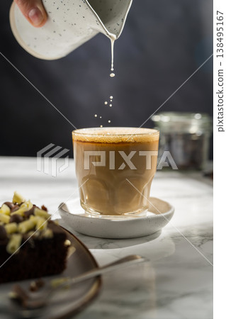 Pouring milk in a glass of coffee, hot latte drink Pouring milk in a glass of coffee, hot latte drink 138495167