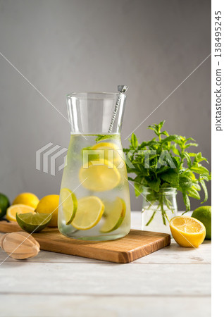 A glass jug with lemonade with lemons, limes and fresh mint, summer drink, bright background 138495245