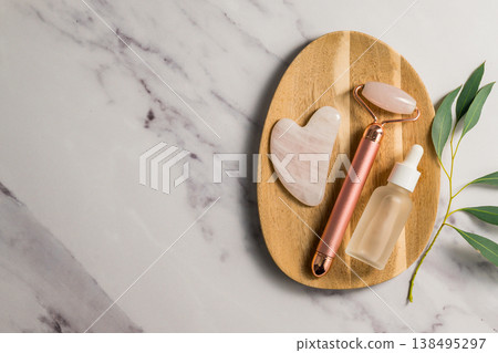 Rose quartz gua sha tool and face massage roller on wooden tray, beauty abstract photo. Top view Rose quartz gua sha tool and face massage roller on wooden tray, beauty abstract photo. Top view 138495297