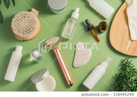 Rose quartz gua sha tool and face massage roller on green background, beauty abstract photo. Top view 138495299