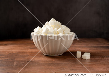 White sugar cubes in a white bowl on wooden background. 138495304