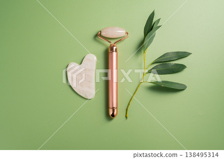 Gua sha tool and face massage roller on green background, beauty abstract photo. Top view. 138495314