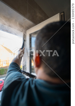 Cleaning the window. A man with steam device removes dirt from the plastic window frame. 138495379