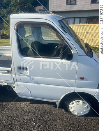 The exterior of a white Japanese light truck/compact truck parked in a rural area. 138497252
