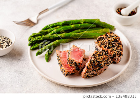 Tuna steak fried in sesame seeds served with asparagus. 138498315