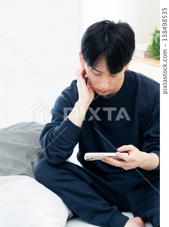 年輕人在床上觀看智能手機 138498535