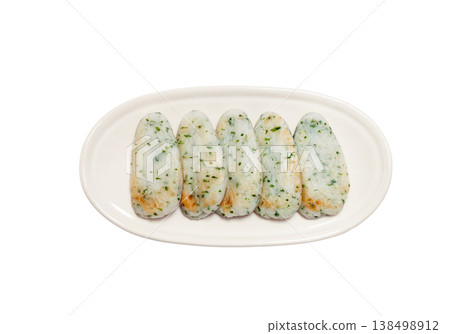 Bamboo leaf-wrapped fish cake with green shiso on a plate [White background, cutout] 138498912