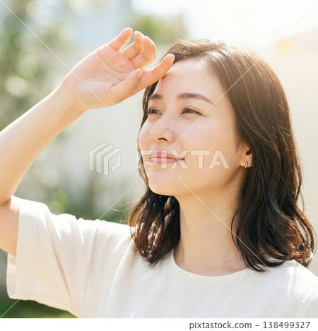 A young woman looks up at the sunlight, embodying summer sun protection and a refreshing beauty image. 138499327