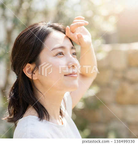 A young woman looks up at the sunlight, embodying summer sun protection and a refreshing beauty image. 138499330