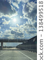 Highway road under overpass with dramatic clouds and bright sun rays in blue sky for transport travel scene 138499518