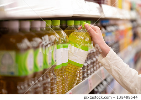 A shopper's hands as they choose a bottle of tea. 138499544