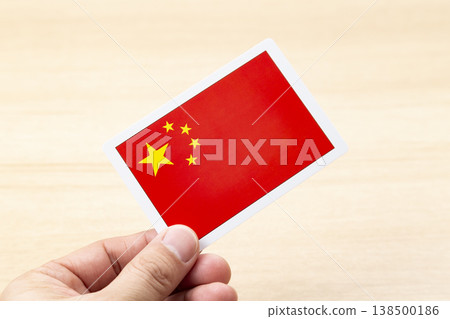 A hand holding a Chinese flag card 138500186