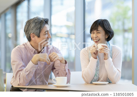 一對六十多歲的夫婦面帶笑容，在咖啡館放鬆休息。 138501005
