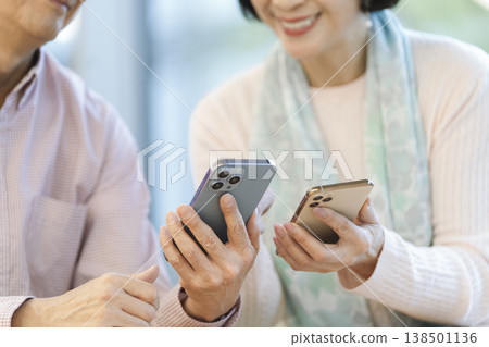 Hands of middle-aged men and women holding smartphones in a cafe 138501136