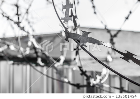 Barbed wire fence with a prison or closed facility fence Barbed wire fence with a prison or closed facility fence 138501454