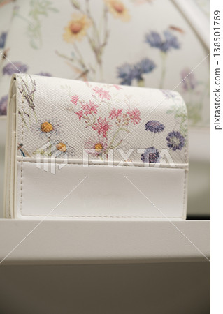 Decorative flower-pattern wallet displayed on a shelf in a store showcasing colorful floral design Decorative flower-pattern wallet displayed on a shelf in a store showcasing colorful floral design 138501769