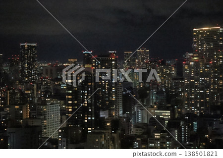 夜幕降臨，城市天際線被霓虹燈照亮的摩天大樓群所環繞。 138501821