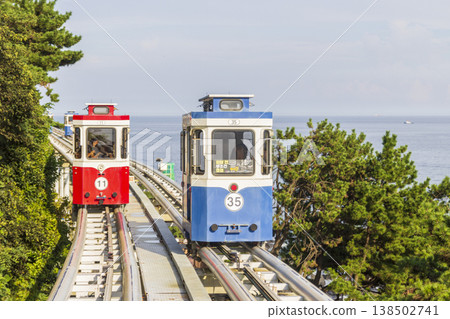 Colorful oceanfront capsule cars travel along an elevated coastal rail, offering scenic seaside views and a relaxed tourism experience over the water. High quality photo Colorful oceanfront capsule cars travel along an elevated coastal rail, offering scenic seaside views and a relaxed tourism experience over the water. High quality photo 138502741