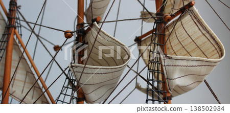 Masts of Sailing Ship. Closeup Detail of Mast and Sails. Crows nest, mast, and canvas sails can be seen in this closeup detail of an old time wooden sailing ship model 138502984