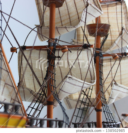 Wooden sail pulleys and ropes of a traditional sailing ship scale model, with rigging, mast and sails and a clean white background 138502985