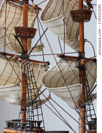 Web of rigging ropes over sails on masts background. Old sailing ship model with wooden masts and sails Web of rigging ropes over sails on masts background. Old sailing ship model with wooden masts and sails 138502986