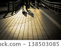 A photograph of the silhouettes of a young couple walking in front of Shibuya Station. 138503085