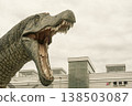 A photo of a dinosaur monument with its mouth wide open in the plaza at the west exit of JR Fukui Station. 138503087