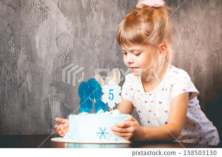 The child blows out the candles on the cake.  138503130