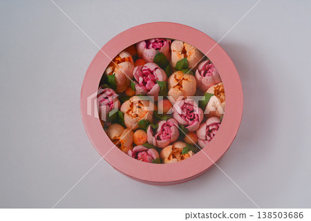 A pink round box with marshmallow flowers on a white background. 138503686