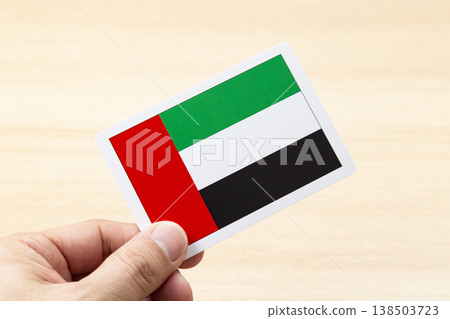 A hand holding a card with the flag of the United Arab Emirates. 138503723