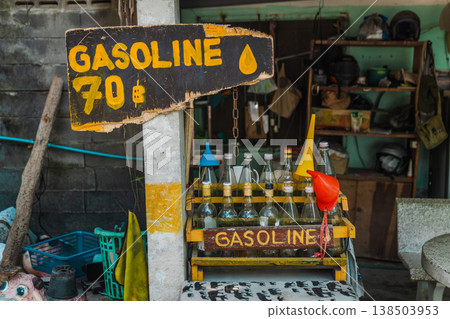Hand painted gasoline price sign and glass bottles with fuel at small roadside shop on Koh Samui, informal petrol sale setup in Thailand Hand painted gasoline price sign and glass bottles with fuel at small roadside shop on Koh Samui, informal petrol sale setup in Thailand 138503953