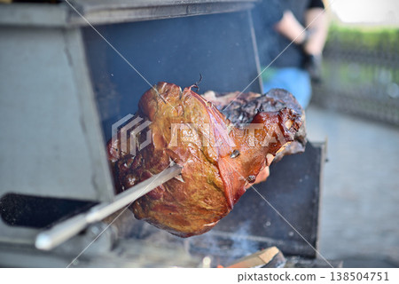 Roasted meat on rotisserie spit over outdoor bbq grill Roasted meat on rotisserie spit over outdoor bbq grill 138504751