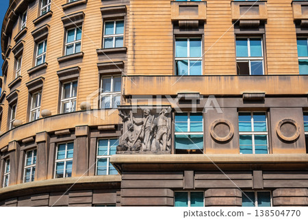 Historic curved building facade with windows and relief sculpture 138504770