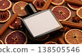 Perfume Bottle with Blank Label Surrounded by Dried Orange Slices and Cinnamon Sticks on Wooden Surface 138505546