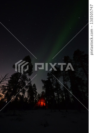 In Inari, in the Finnish Lapland region, a fantastical green aurora appeared above a snow-covered cottage. 138505747