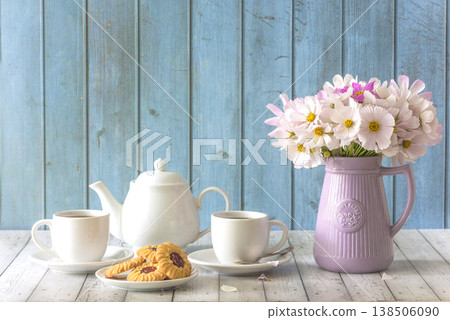 Two white cups of tea, tea pot, cookies and bouquet of pink cosmos flowers on a wooden background; copy space Two white cups of tea, tea pot, cookies and bouquet of pink cosmos flowers on a wooden background; copy space 138506090