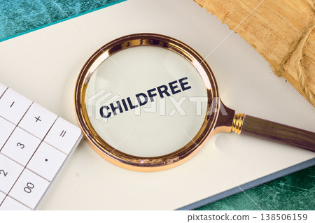 A magnified view reveals the word CHILDFREE, a significant concept, nestled on a book with a calculator nearby, suggesting life choices and planning A magnified view reveals the word CHILDFREE, a significant concept, nestled on a book with a calculator nearby, suggesting life choices and planning 138506159