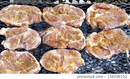 Top view of pork steaks sizzle on home grill as the surface slowly browns. Smoke rises gently into air while meat cooks evenly over steady heat, capturing rich atmosphere of relaxed backyard barbecue Top view of pork steaks sizzle on home grill as the surface slowly browns. Smoke rises gently into air while meat cooks evenly over steady heat, capturing rich atmosphere of relaxed backyard barbecue 138506332
