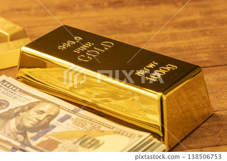 Gold Bullion Bar with US Dollar Bills on Wooden Table - Investment and Wealth Symbols 138506753