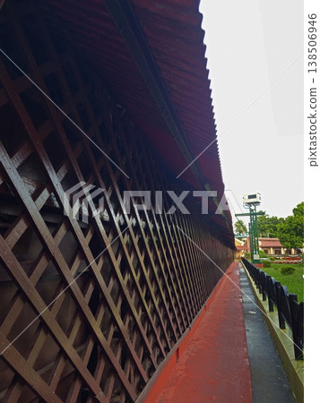 A long, perspective view of a wooden lattice walkway and red-roofed corridor within the Cellular Jail complex. A long, perspective view of a wooden lattice walkway and red-roofed corridor within the Cellular Jail complex. 138506946