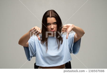 Young woman giving a double thumbs down sign, expressing disappointment, strong disagreement, and dissatisfaction Young woman giving a double thumbs down sign, expressing disappointment, strong disagreement, and dissatisfaction 138507086