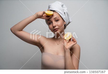 Young woman with a towel wrapped around her head holding two lemon halves, symbolizing natural skincare, beauty, facial care, and wellness using fresh citrus ingredients Young woman with a towel wrapped around her head holding two lemon halves, symbolizing natural skincare, beauty, facial care, and wellness using fresh citrus ingredients 138507167