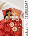 Two women are sleeping on a bed with a red comforter 138508267