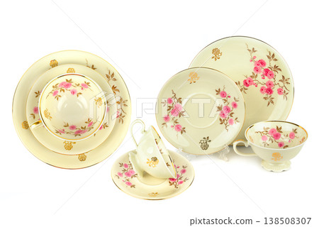 Vintage porcelain tea set with pink floral and gold patterns isolated on white background, antique ceramic cups, saucers, and plates, retro tableware set, elegant home decor, horizontal composition. Vintage porcelain tea set with pink floral and gold patterns isolated on white background, antique ceramic cups, saucers, and plates, retro tableware set, elegant home decor, horizontal composition. 138508307