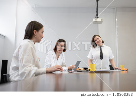 Three women having business breakfast meeting at table in bright office with coffee and orange juice. Breakfast, meeting, business, women, teamwork, office. Three women having business breakfast meeting at table in bright office with coffee and orange juice. Breakfast, meeting, business, women, teamwork, office. 138508398