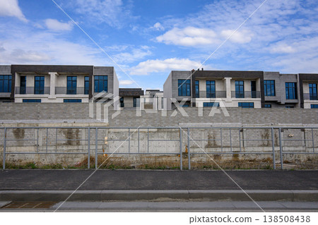 Modern houses behind concrete barrier under blue sky Modern houses behind concrete barrier under blue sky 138508438